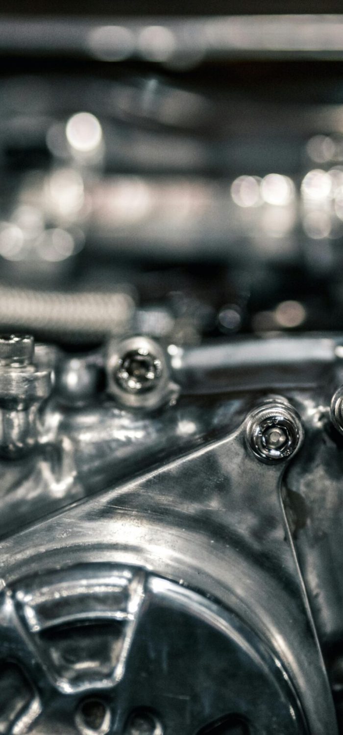 Macro shot of a polished metallic engine component with secure bolts and tension pulleys in a high-precision machine setup