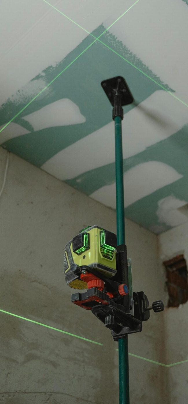 Distance laser sensor mounted on extension pole for ceiling alignment and construction measurement